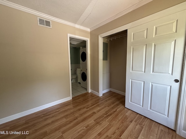 248 Lakeside Villa Unit J, Diamondhead, MS 39525 - unfurnished bedroom featuring crown molding, stacked washer / drying machine, visible vents, baseboards, and wood finished floors