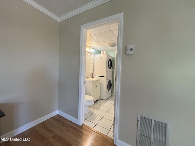 248 Lakeside Villa Unit J, Diamondhead, MS 39525 - clothes washing area with stacked washing maching and dryer, light wood-type flooring, crown molding, visible vents, and baseboards