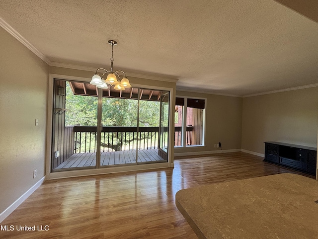248 Lakeside Villa Unit J, Diamondhead, MS 39525 - unfurnished dining area with wood finished floors, a chandelier, ornamental molding, baseboards, and a textured ceiling