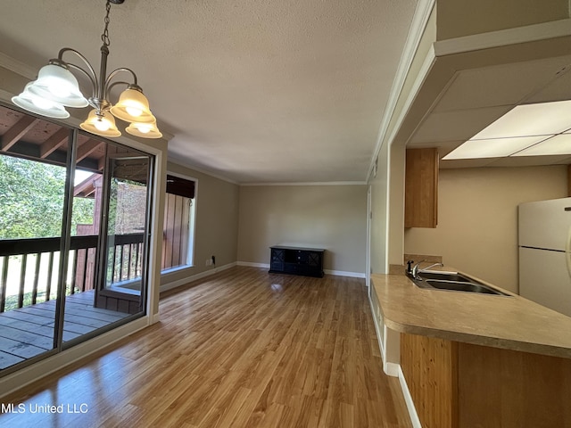 248 Lakeside Villa Unit J, Diamondhead, MS 39525 - unfurnished living room with crown molding, a sink, light wood-style floors, a chandelier, and baseboards