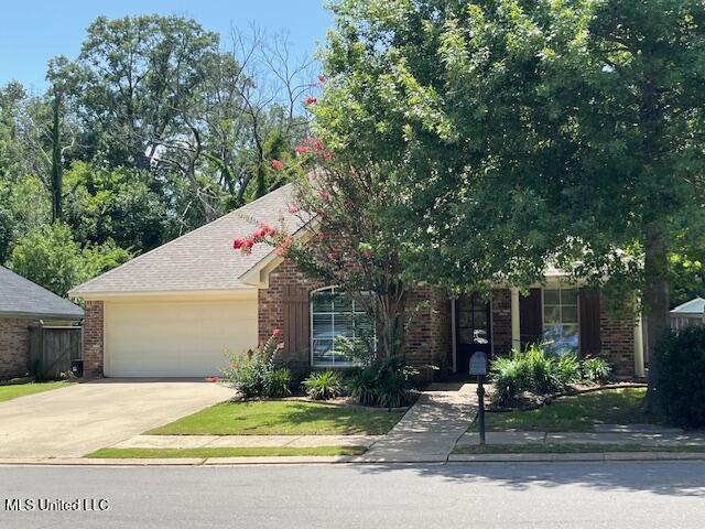 104 Blackstone Cir, Brandon, MS 39047 - view of property hidden behind natural elements with brick siding, an attached garage, and concrete driveway