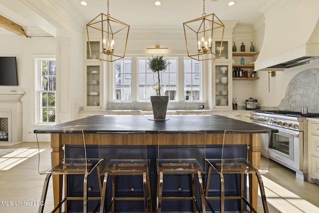 kitchen featuring custom range hood, stainless steel stove, an inviting chandelier, and a spacious island