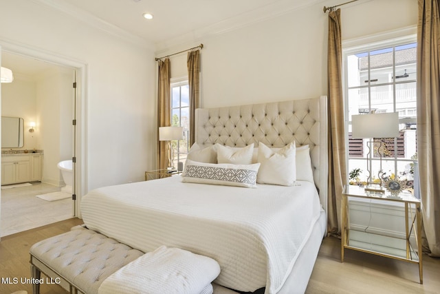 bedroom with ornamental molding, connected bathroom, and light wood-type flooring