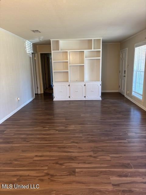 unfurnished living room with crown molding, visible vents, dark wood finished floors, and baseboards