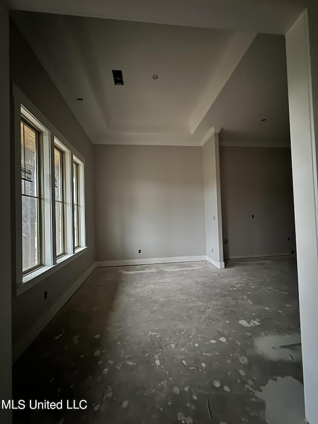 empty room featuring a raised ceiling and baseboards