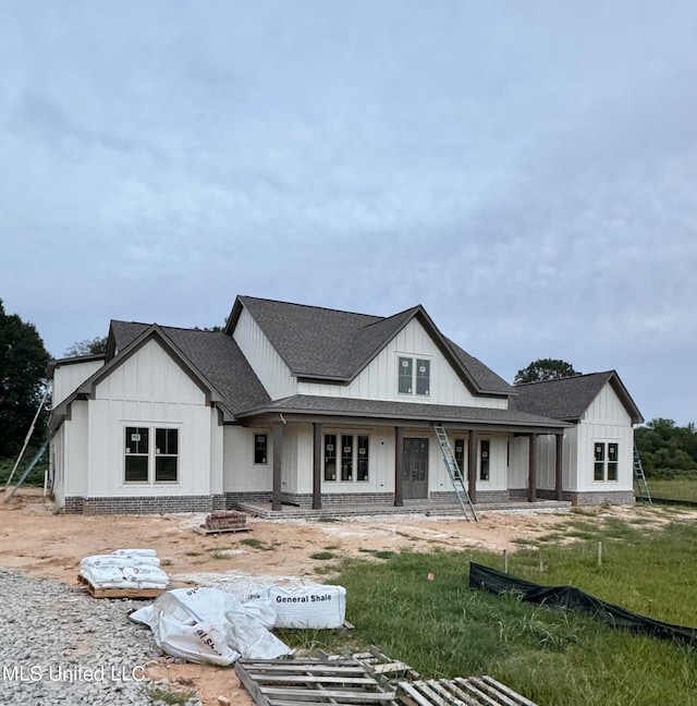 modern farmhouse with a fire pit, brick siding, board and batten siding, and a shingled roof