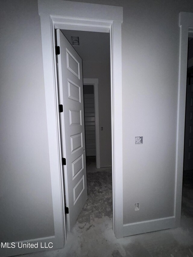 corridor with concrete flooring and baseboards