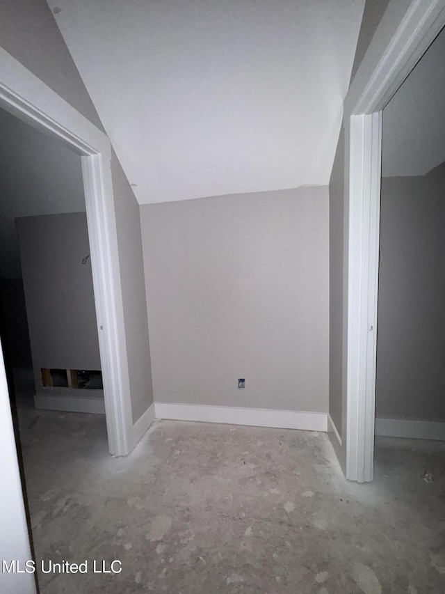 bonus room featuring baseboards, unfinished concrete floors, and vaulted ceiling