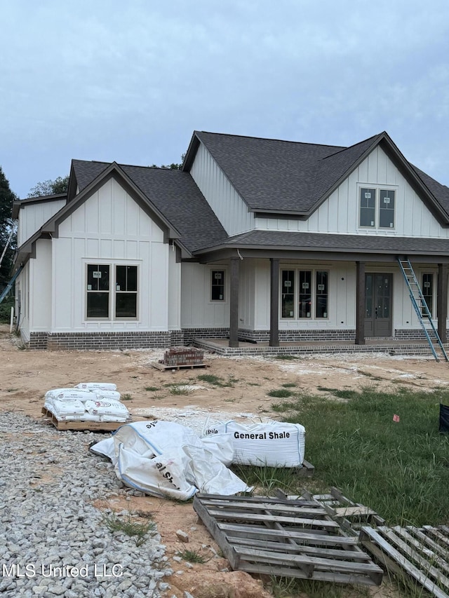 modern inspired farmhouse with brick siding, board and batten siding, and a shingled roof