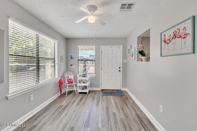 foyer with light hardwood / wood-style flooring, a textured ceiling, and ceiling fan