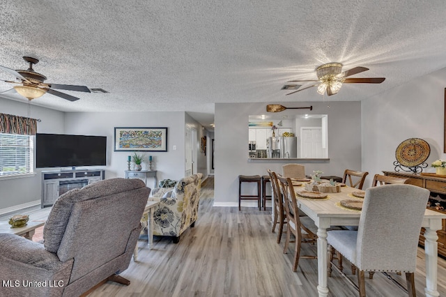 dining area featuring a textured ceiling, light wood-type flooring, and ceiling fan