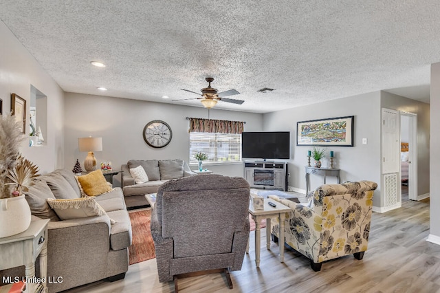 living room with a textured ceiling, light hardwood / wood-style floors, and ceiling fan