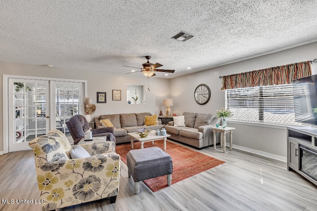 living room featuring a textured ceiling, light wood-type flooring, and ceiling fan