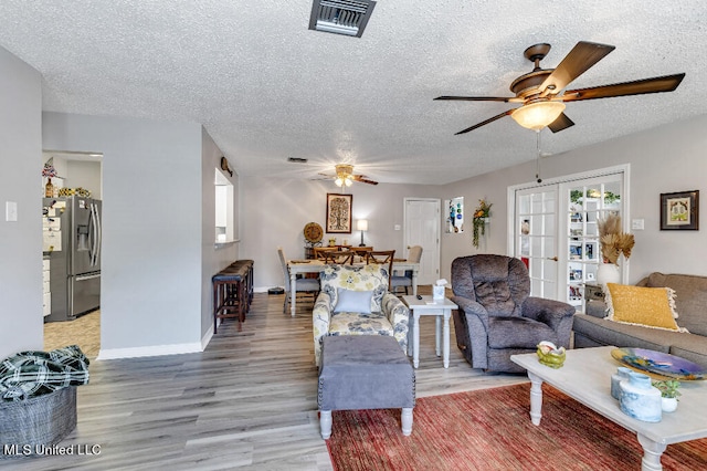 living room featuring a textured ceiling, hardwood / wood-style flooring, and ceiling fan