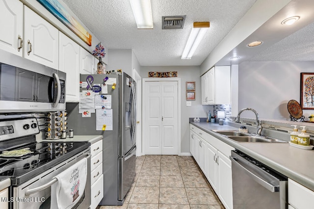 kitchen featuring white cabinets, light tile patterned floors, a textured ceiling, sink, and stainless steel appliances