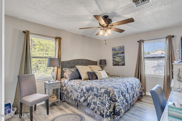 bedroom featuring light hardwood / wood-style flooring, a textured ceiling, and ceiling fan