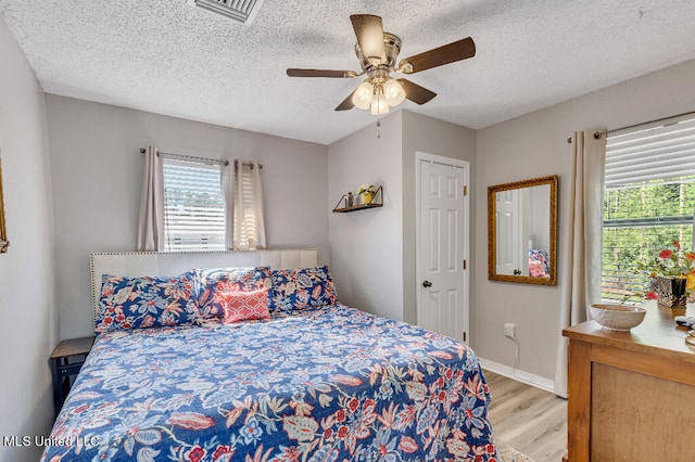 bedroom with a textured ceiling, light hardwood / wood-style floors, and ceiling fan