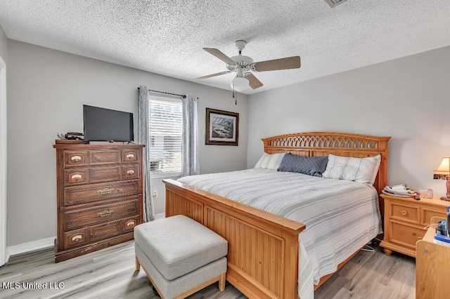 bedroom with light hardwood / wood-style floors, a textured ceiling, and ceiling fan