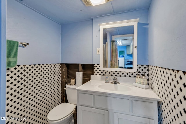 bathroom with toilet, vanity, and tile walls