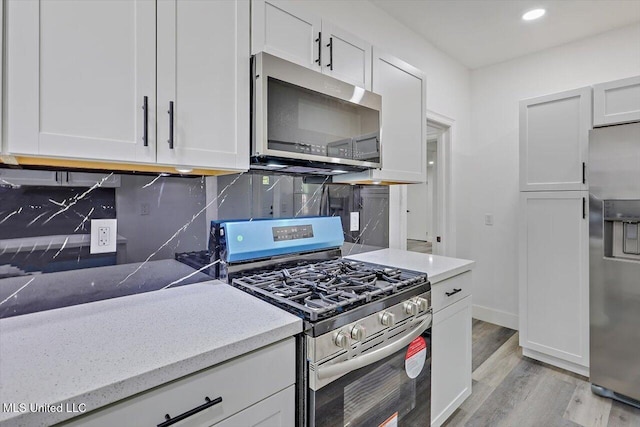 4560 Meadowridge Dr, Jackson, MS 39206 - kitchen featuring stainless steel appliances, tasteful backsplash, light wood-style flooring, and white cabinetry