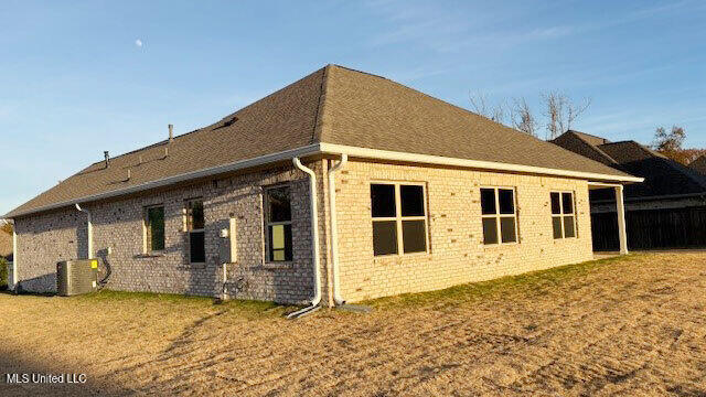 view of side of home with a yard and central AC unit