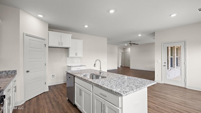 kitchen featuring sink, white cabinetry, light stone counters, stainless steel dishwasher, and an island with sink