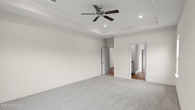 unfurnished bedroom featuring ornamental molding, a raised ceiling, and dark colored carpet