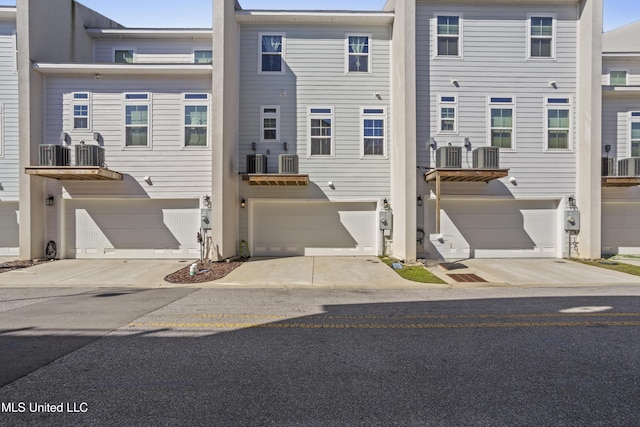 view of front of property with a garage, concrete driveway, and central AC