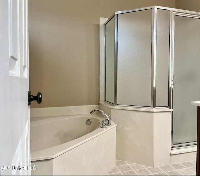 bathroom with a shower stall, a garden tub, and tile patterned flooring