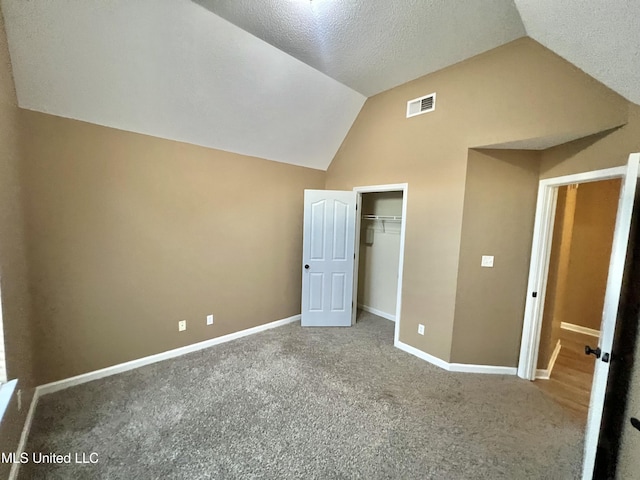 unfurnished bedroom with vaulted ceiling, baseboards, carpet flooring, a closet, and a textured ceiling