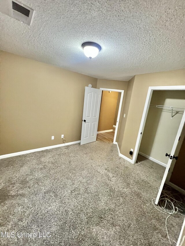 unfurnished bedroom with a textured ceiling, carpet floors, a closet, and baseboards