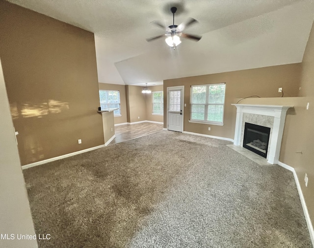 unfurnished living room featuring carpet flooring, ceiling fan, vaulted ceiling, a fireplace, and baseboards
