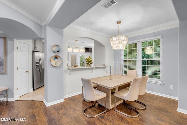 2252 Beach Dr Unit 206, Gulfport, MS 39507 - dining area featuring arched walkways, ornamental molding, a chandelier, and wood finished floors