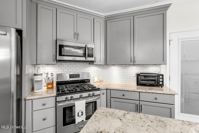 2252 Beach Dr Unit 206, Gulfport, MS 39507 - kitchen with appliances with stainless steel finishes, gray cabinetry, backsplash, and light stone countertops