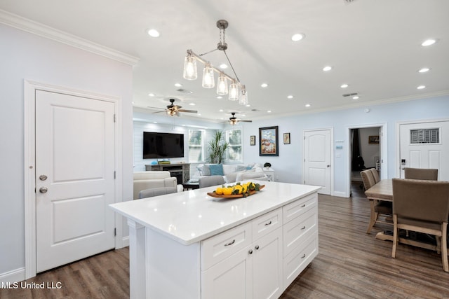 kitchen with ornamental molding, a kitchen island, decorative light fixtures, and dark hardwood / wood-style floors