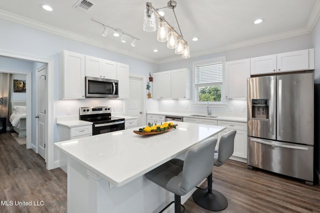 kitchen with stainless steel appliances, dark wood-type flooring, sink, a breakfast bar area, and a kitchen island