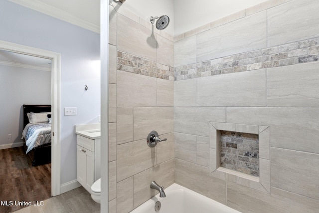 full bathroom with toilet, tiled shower / bath, hardwood / wood-style flooring, vanity, and crown molding