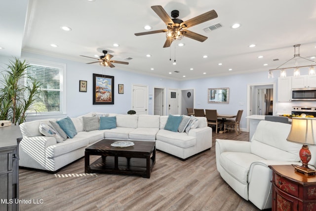 living room featuring light wood-type flooring, ceiling fan, and crown molding