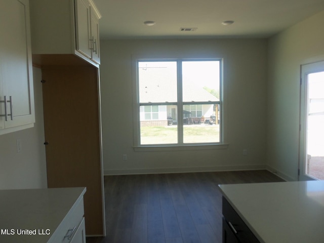 kitchen with light countertops, white cabinets, visible vents, and dark wood-style floors