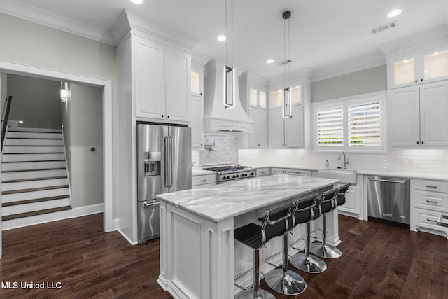 302 Covington Cv, Madison, MS 39110 - kitchen featuring stainless steel appliances, premium range hood, ornamental molding, white cabinetry, and a center island