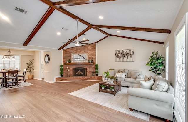 living room featuring light hardwood / wood-style flooring, vaulted ceiling with beams, a textured ceiling, and a fireplace