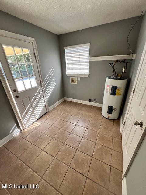 interior space featuring water heater, a textured ceiling, and light tile patterned flooring