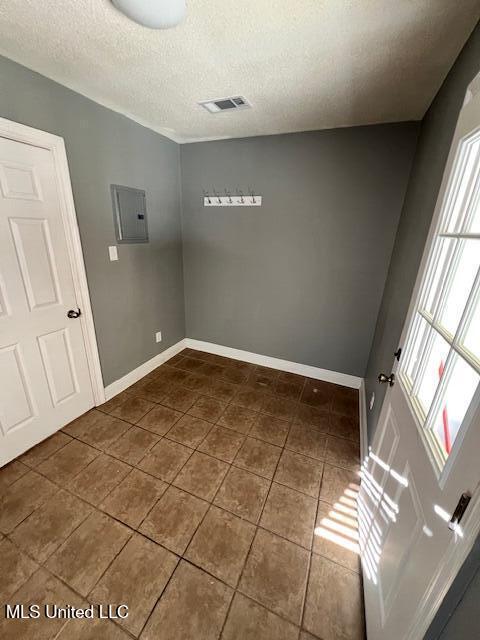 tiled spare room with electric panel and a textured ceiling