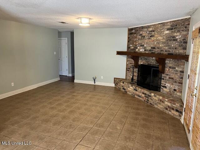 unfurnished living room featuring a brick fireplace and a textured ceiling