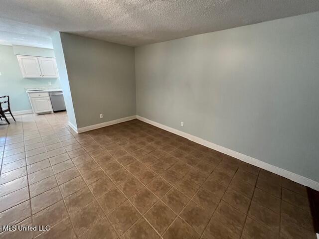 tiled empty room with a textured ceiling