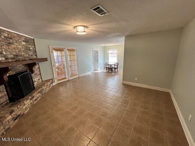 unfurnished living room with a fireplace, tile patterned floors, and a textured ceiling