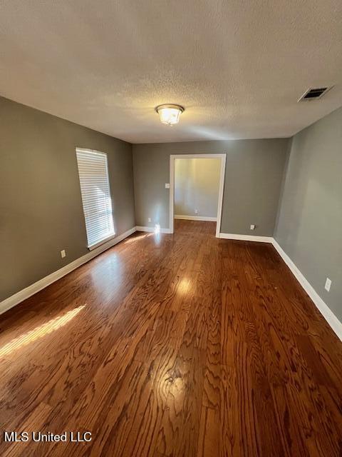 unfurnished room with dark hardwood / wood-style flooring and a textured ceiling