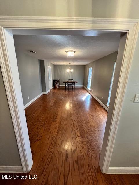 unfurnished dining area with a notable chandelier and wood-type flooring