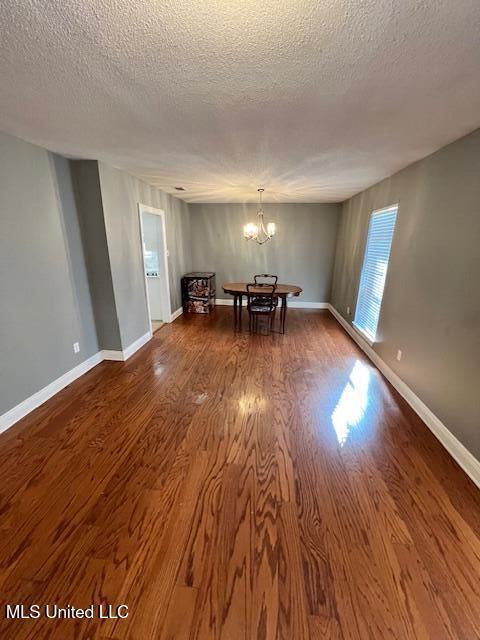 unfurnished dining area featuring a chandelier, hardwood / wood-style floors, and a textured ceiling