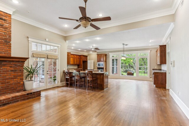 421 Starling Dr, Slidell, LA 70461 - kitchen with stainless steel microwave, wood finished floors, brown cabinets, a ceiling fan, and a kitchen breakfast bar
